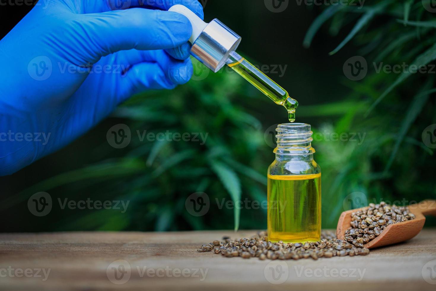 hand olie in een glazen fles gieten. hennep olie product. hennepextract, cbd-olie, medisch marihuanaconcept foto