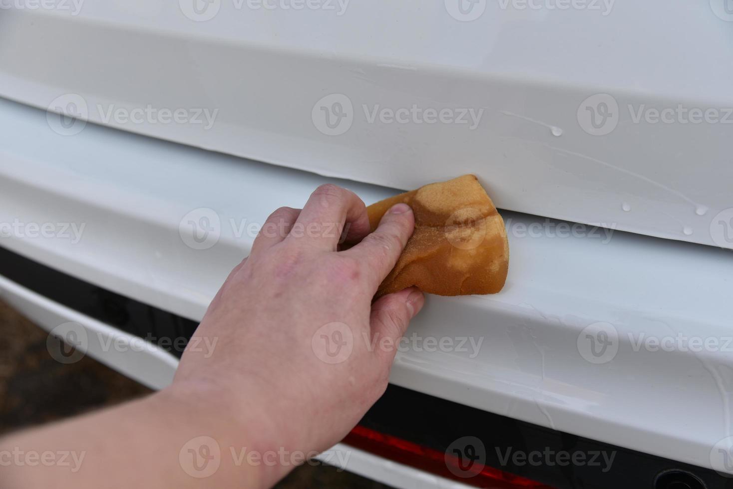 een witte auto met de hand wassen met een spons foto