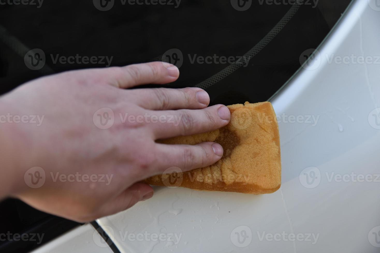 een witte auto met de hand wassen met een spons foto