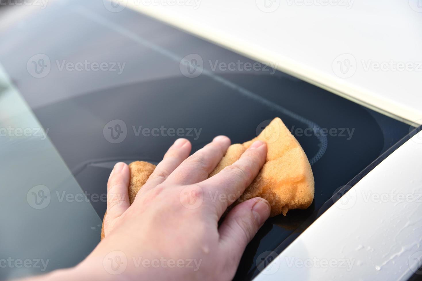 een witte auto met de hand wassen met een spons foto