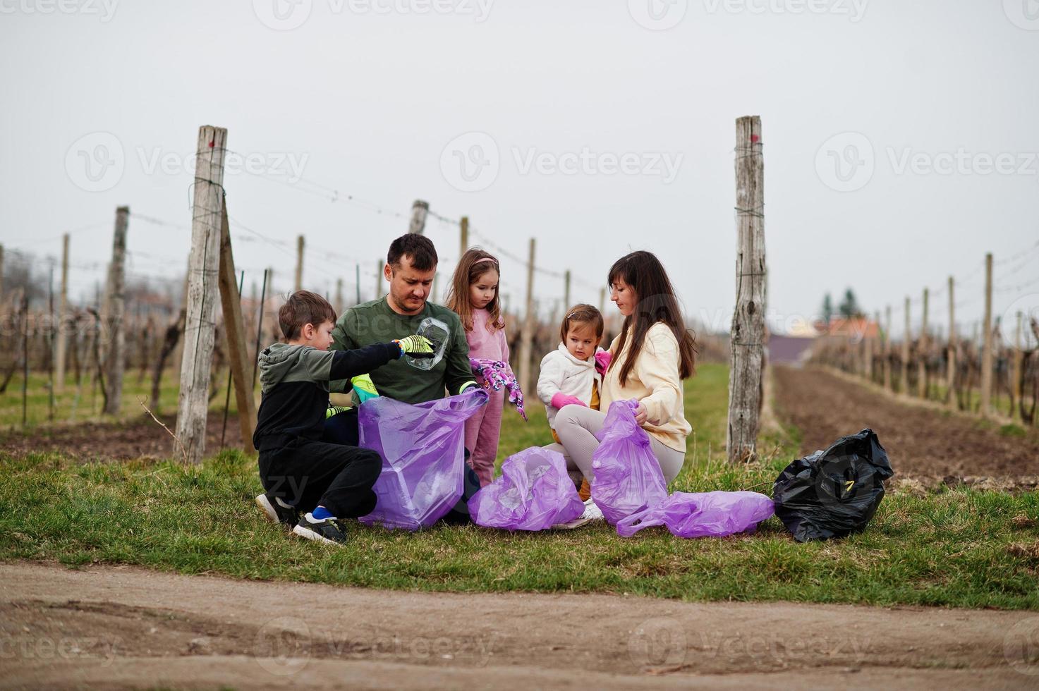 familie met vuilniszak die afval verzamelt tijdens het schoonmaken in de wijngaarden. milieubehoud en ecologie, recycling. foto