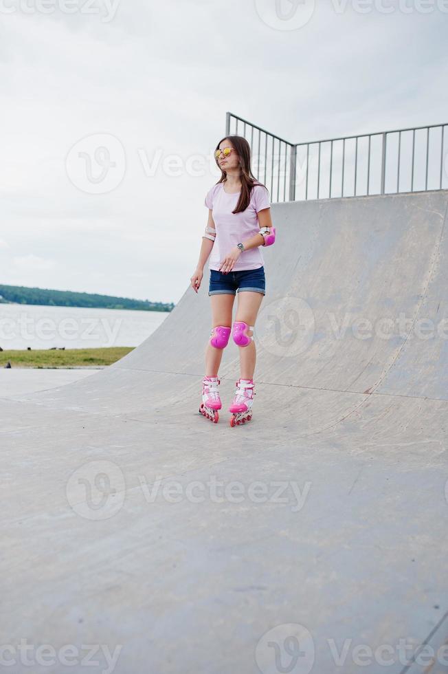 portret van een fantastische jonge vrouw skaten op de buiten rolschaatsbaan. foto