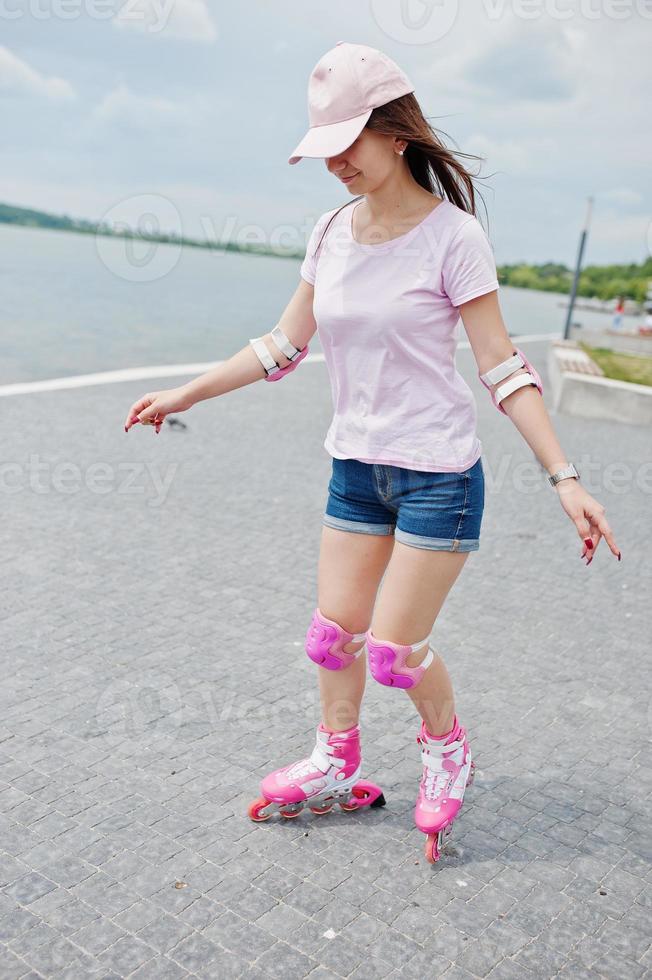 portret van een knappe jonge vrouw in casual kleding skaten op de stoep in het park. foto