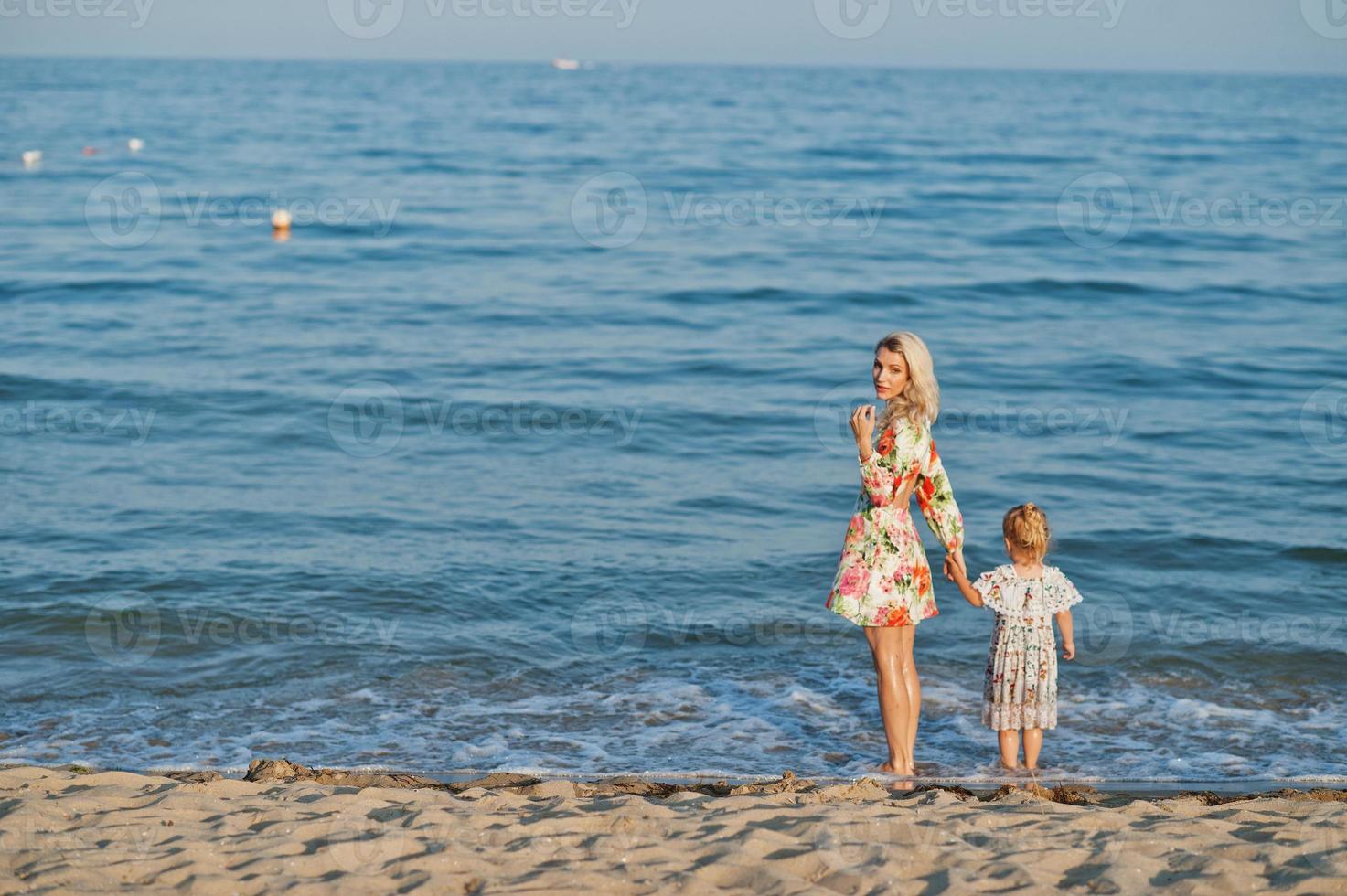 moeder en mooie dochter hebben plezier op het strand. portret van gelukkige vrouw met schattig klein meisje op vakantie. foto