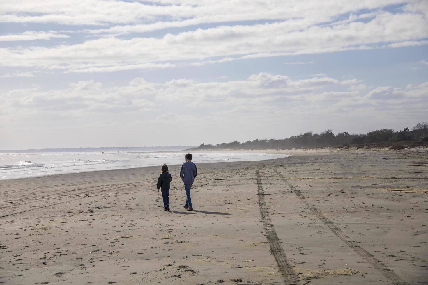 broer en zus wandelen op een zandstrand foto