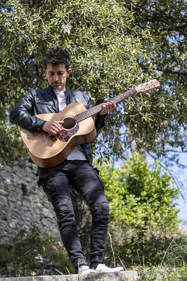 jongen speelt gitaar in de natuur foto