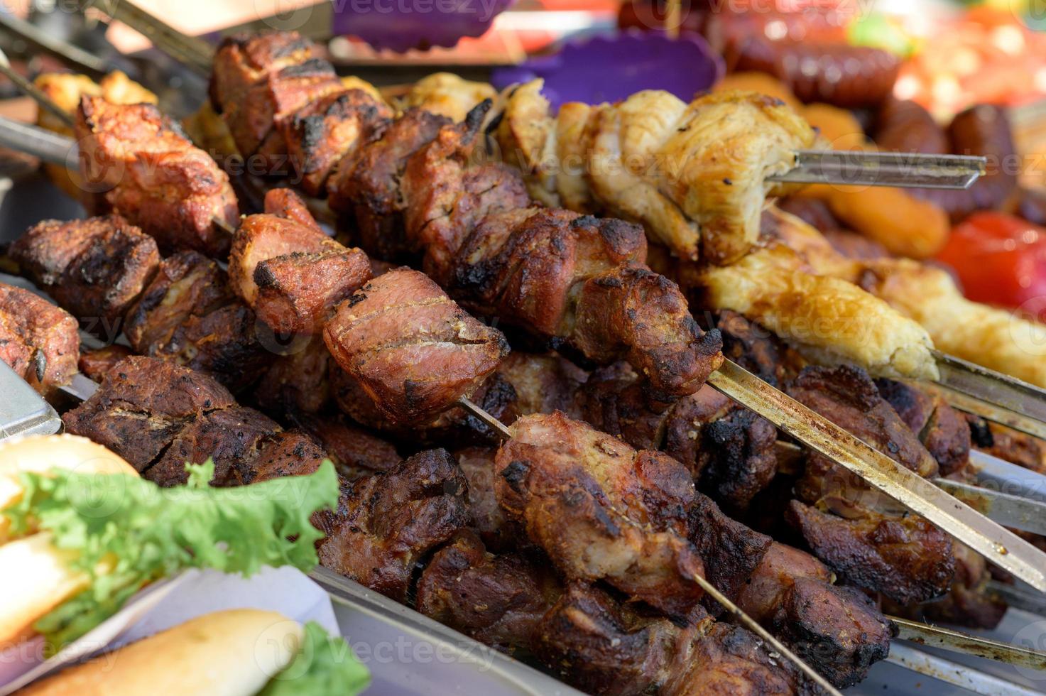 gegrilde worst met toevoeging van kruiden en groenten op de grillplaat, buitenshuis. grillen van voedsel, bbq, barbecue foto