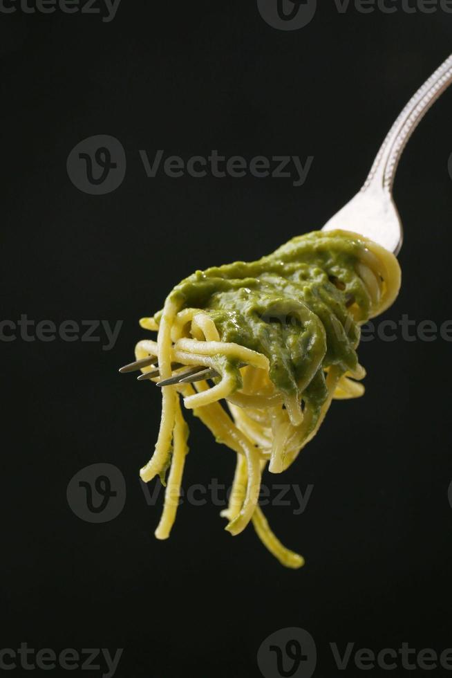 Italiaanse pasta spaghetti op vork op zwarte achtergrond foto