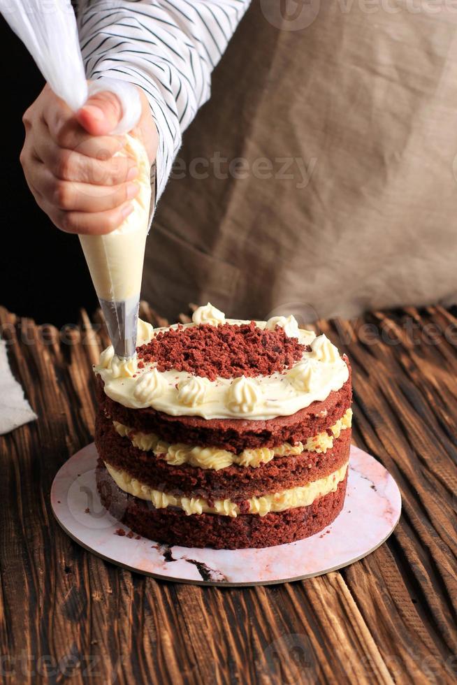 vrouwelijke Aziatische hand versieren tiramisu met swirl mascarpone met spuitzak foto