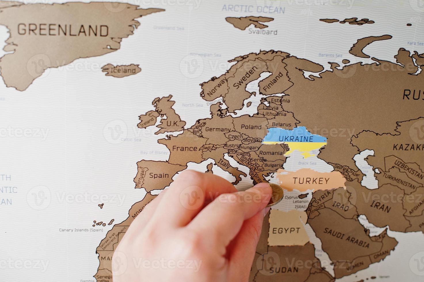 kras reiskaart van de wereld. hand van man wissen Europa Turkije met munt. foto