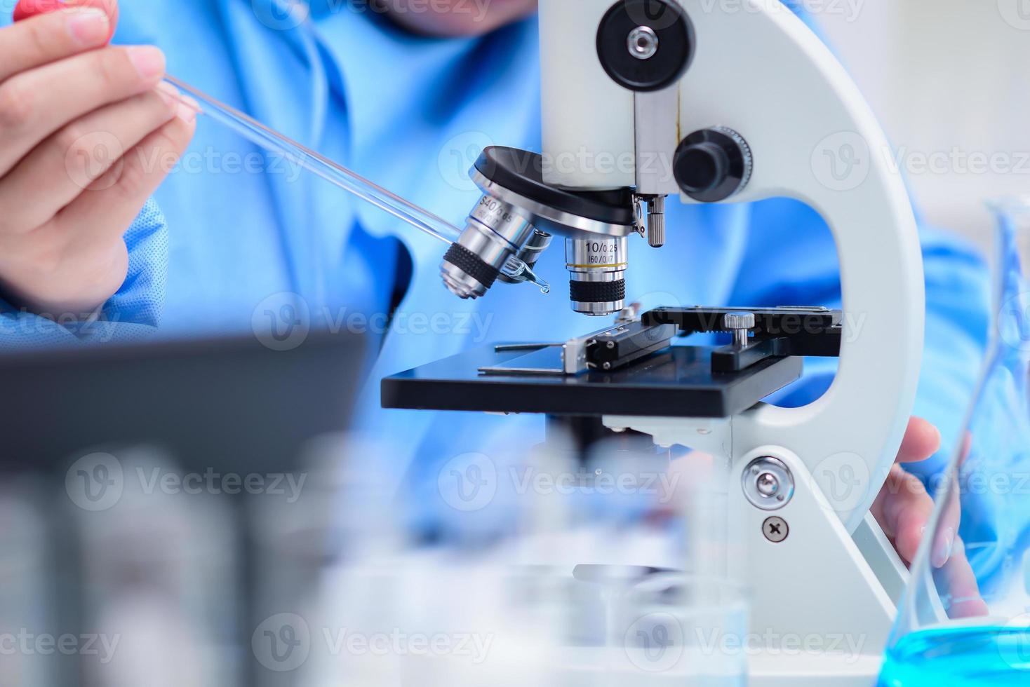 wetenschappers bereiden monsters voor om de monsters met een microscoop in het laboratorium te onderzoeken, waarbij ze de oplossing op een glasplaat laten vallen met een pipet op de microscoop. ,farmaceutisch concept,uitvinder van het vaccin foto