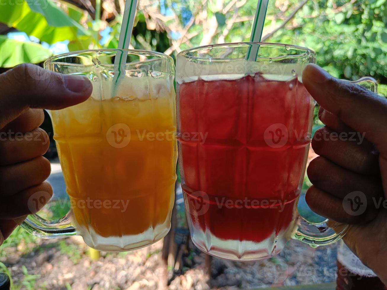 vrienden juichen een glas sinaasappelsap en rosellesap toe om af te koelen in de zomer foto