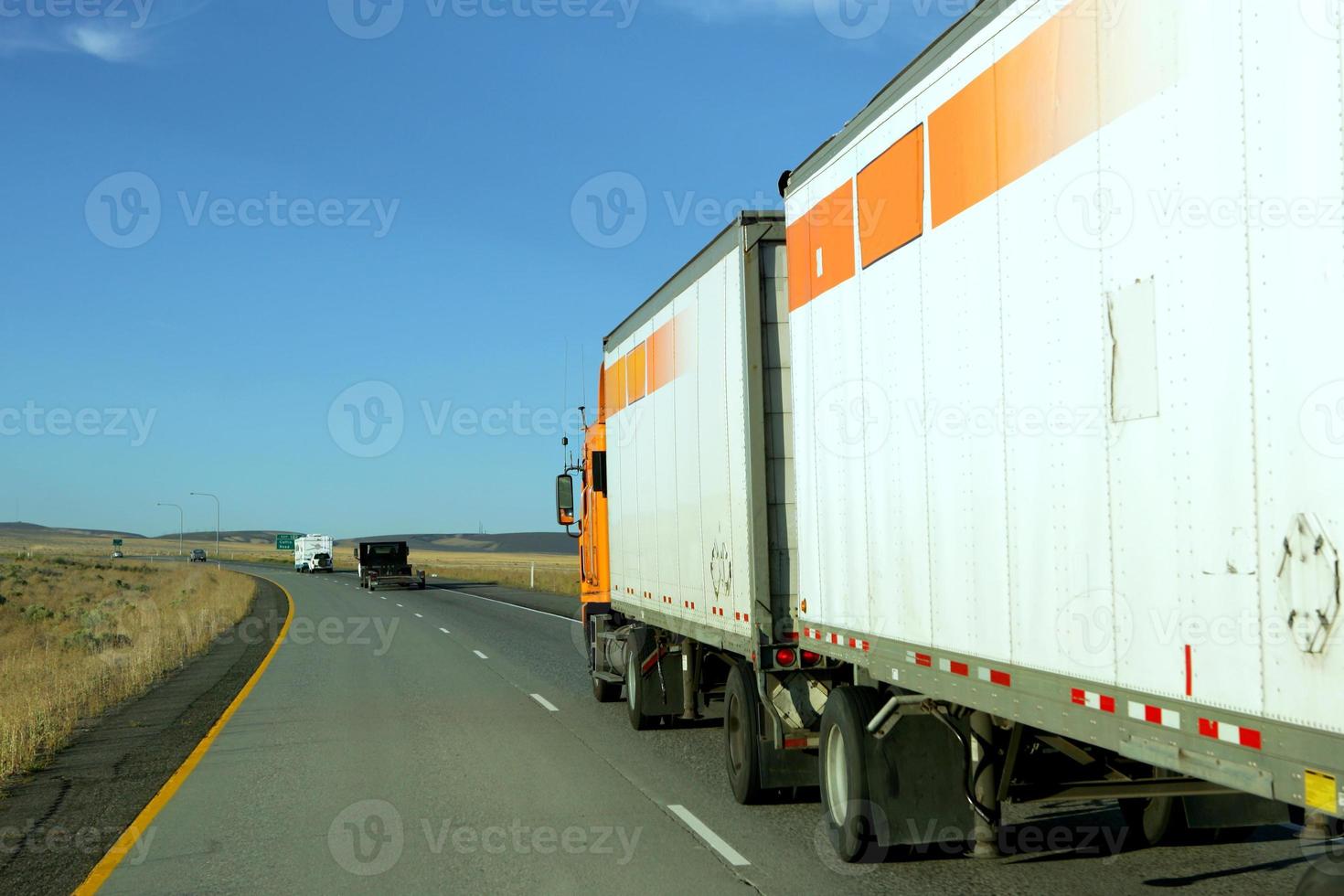 zijaanzicht van vrachtwagen rijden achter andere vrachtwagens op de snelweg foto