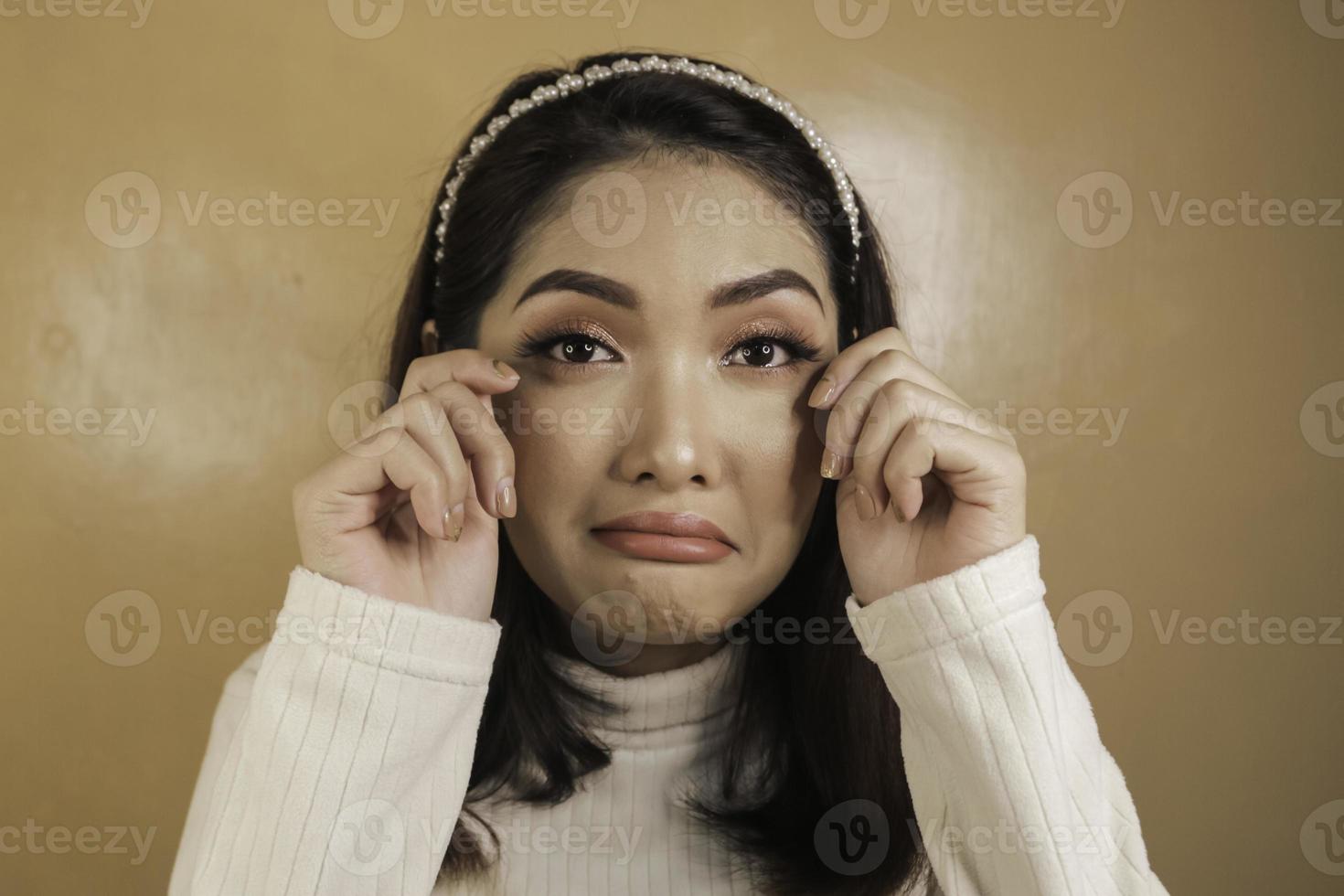 tranen vergieten en droevige uitdrukking van jonge Aziatische vrouw in wit overhemd foto