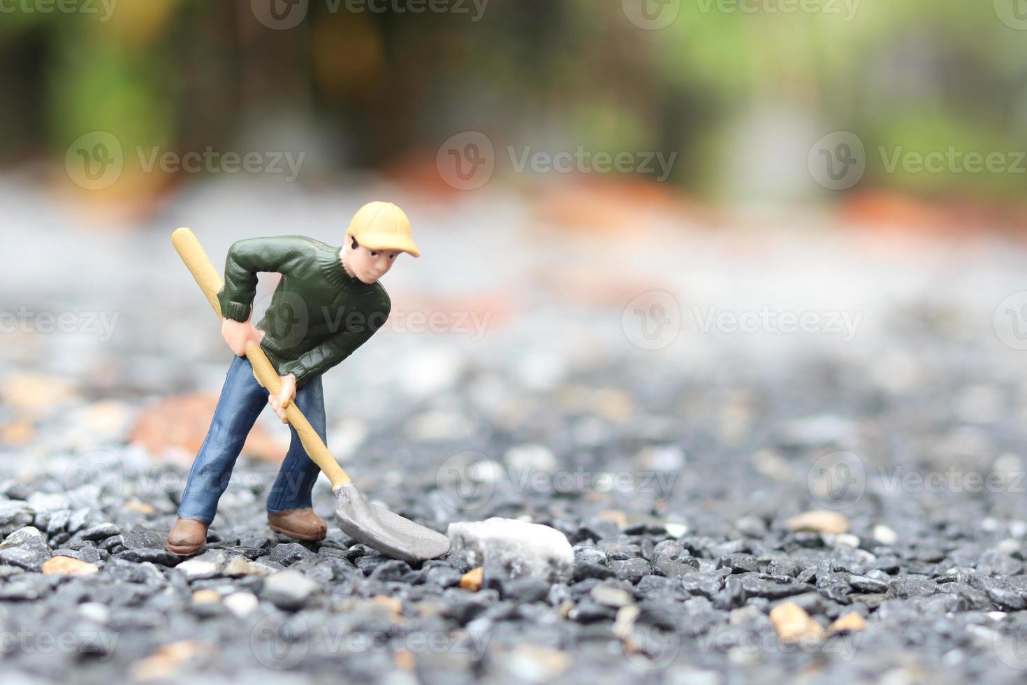 miniatuur werkpop met schop om te werken, mijnwerker man aan het werk klein figuur speelgoedmodel grond graven of tuinieren foto