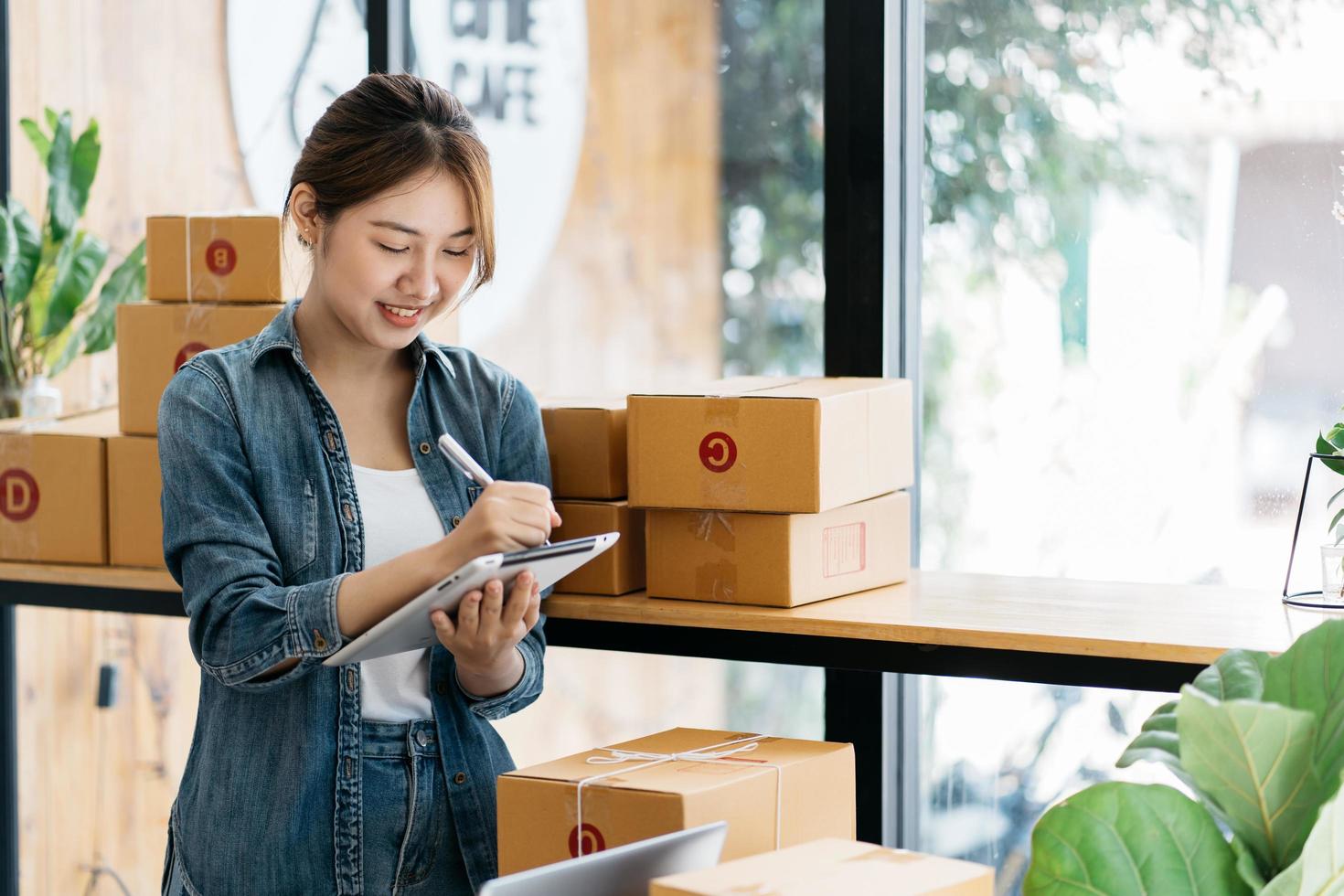 werknemer in magazijn die vakjes aanvinkt met behulp van digitale tablet.start kleine ondernemer mkb of freelance vrouw die thuis werkt, jonge Aziatische eigenaar van een klein bedrijf, online marketing. foto