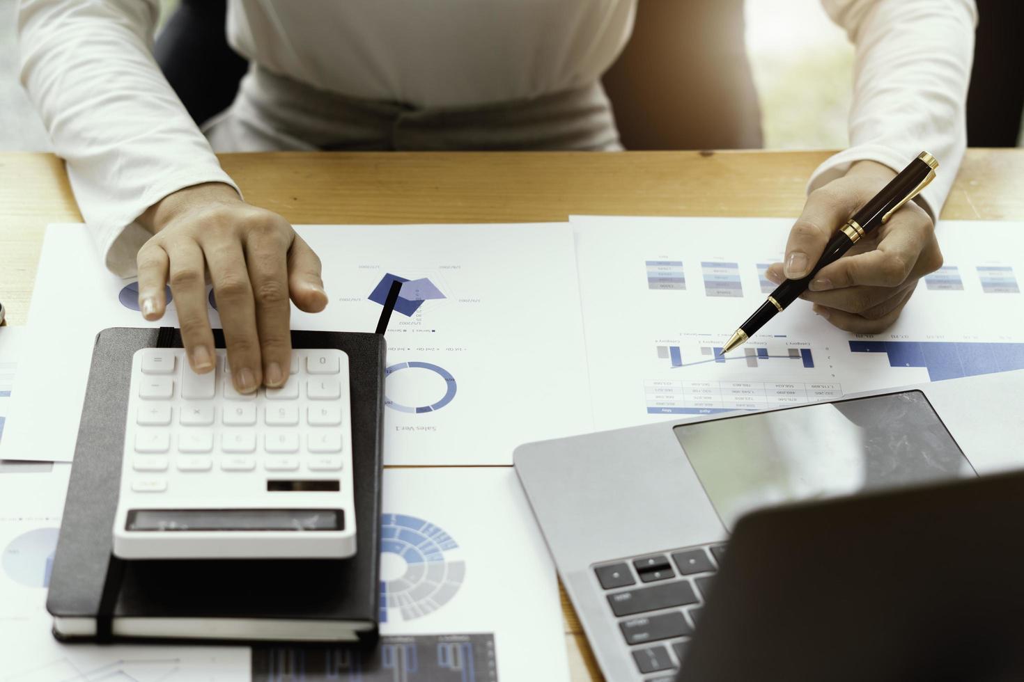 close-up zakenman en partner met behulp van rekenmachine en laptop voor het berekenen van financiën, belastingen, boekhouding, statistiek en analytisch onderzoeksconcept foto