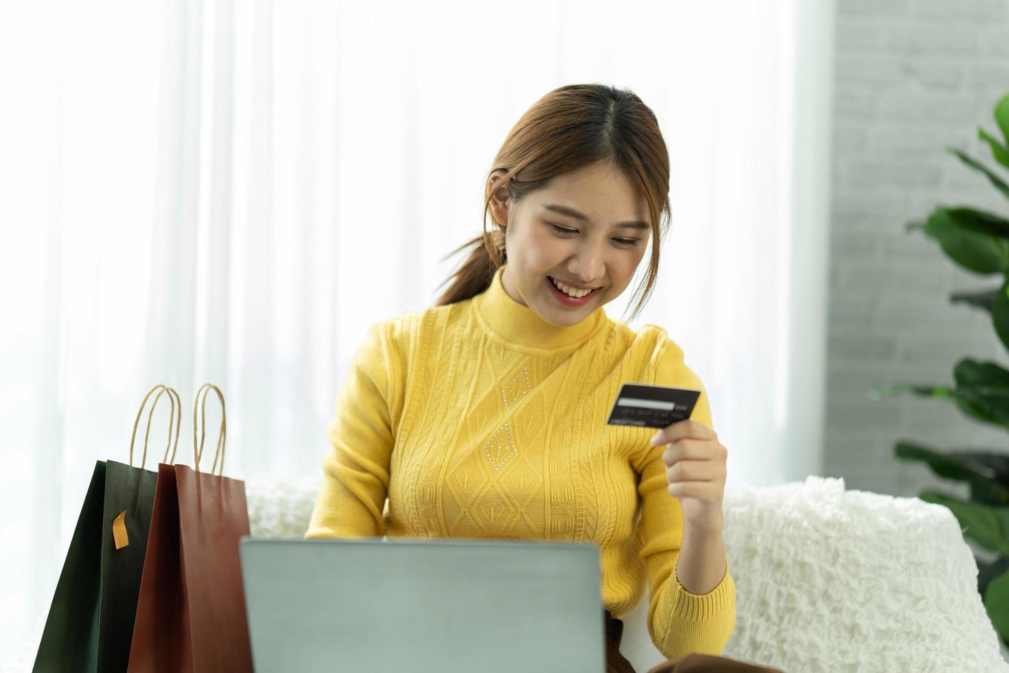 aziatische vrouw in vrijetijdskleding is blij en vrolijk terwijl ze communiceert met haar smartphone en in een coffeeshop werkt. foto