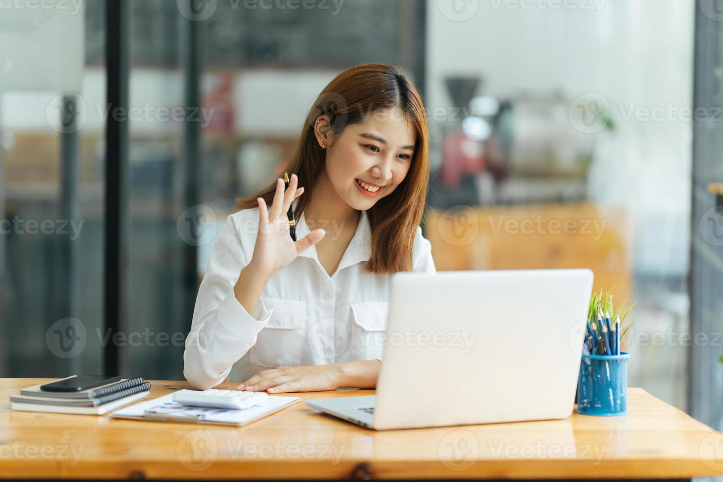 online vergadering. gelukkige jonge vrouw die een laptop gebruikt voor virtuele conferenties, met een videogesprek thuis. vrolijke aziatische vrouw die op afstand communiceert met collega's, vrienden. foto