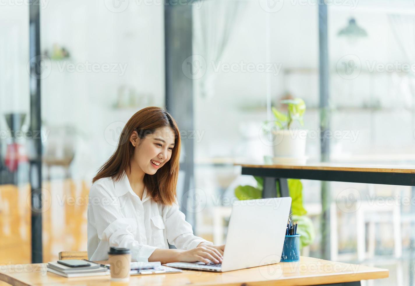 portret van Aziatische jonge vrouw die op laptop en financieel verslag op kantoor werkt. foto