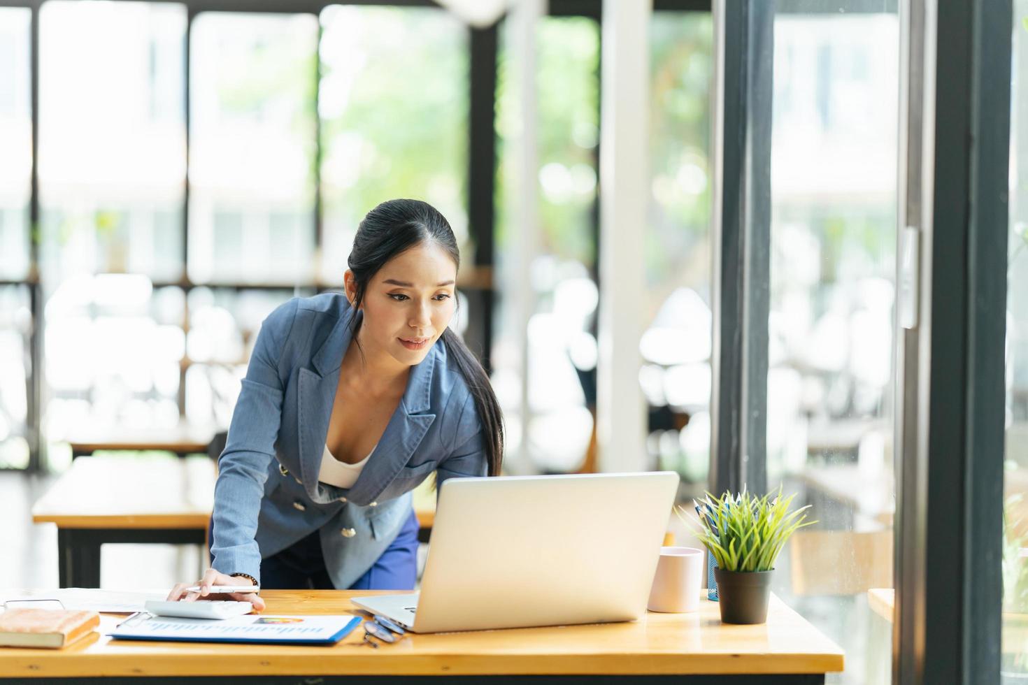 mooie aziatische vrouw denkt ideeën met laptopcomputer in coffeeshop foto