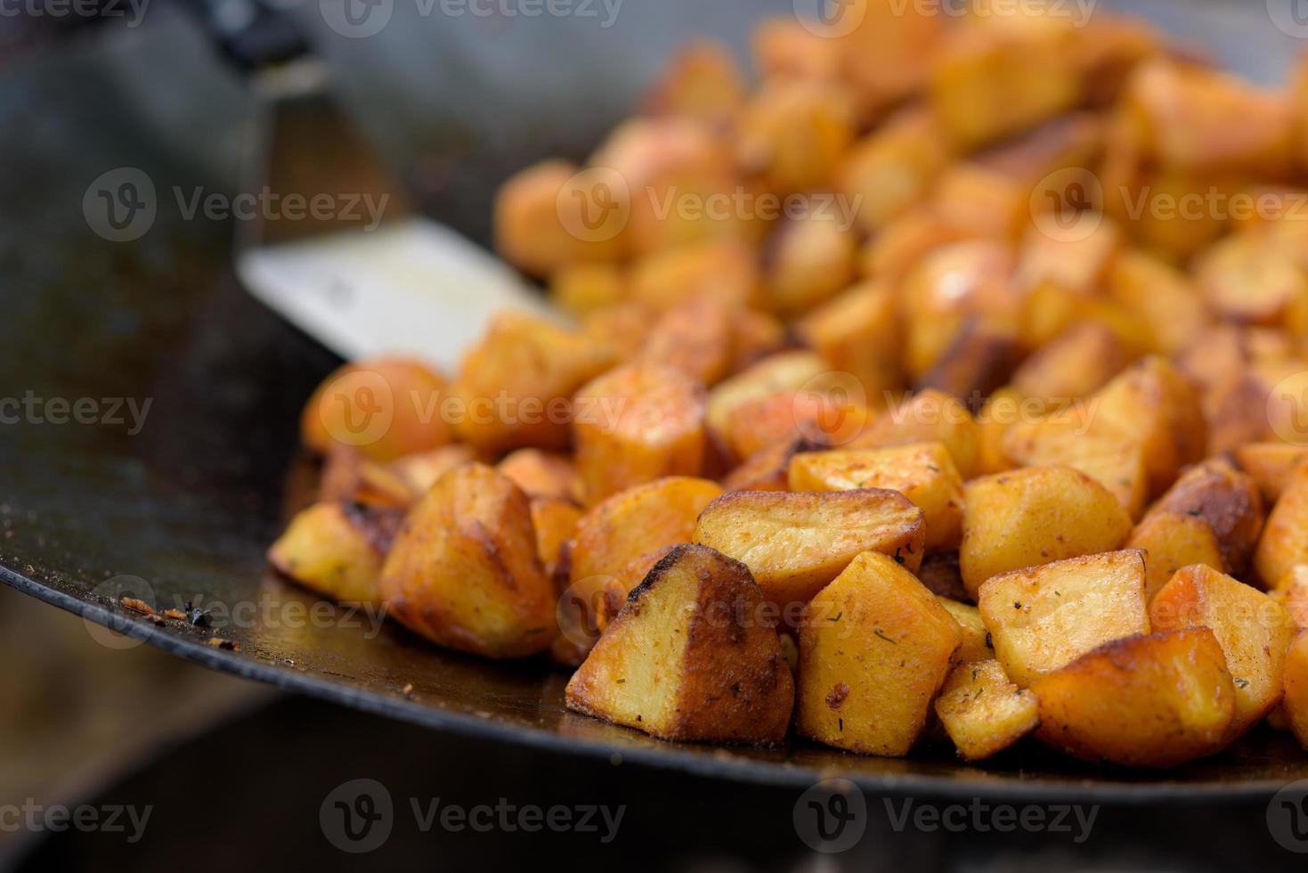 Brokken gebakken aardappelen in een grote koekenpan tijdens het straatvoedselfestival. foto