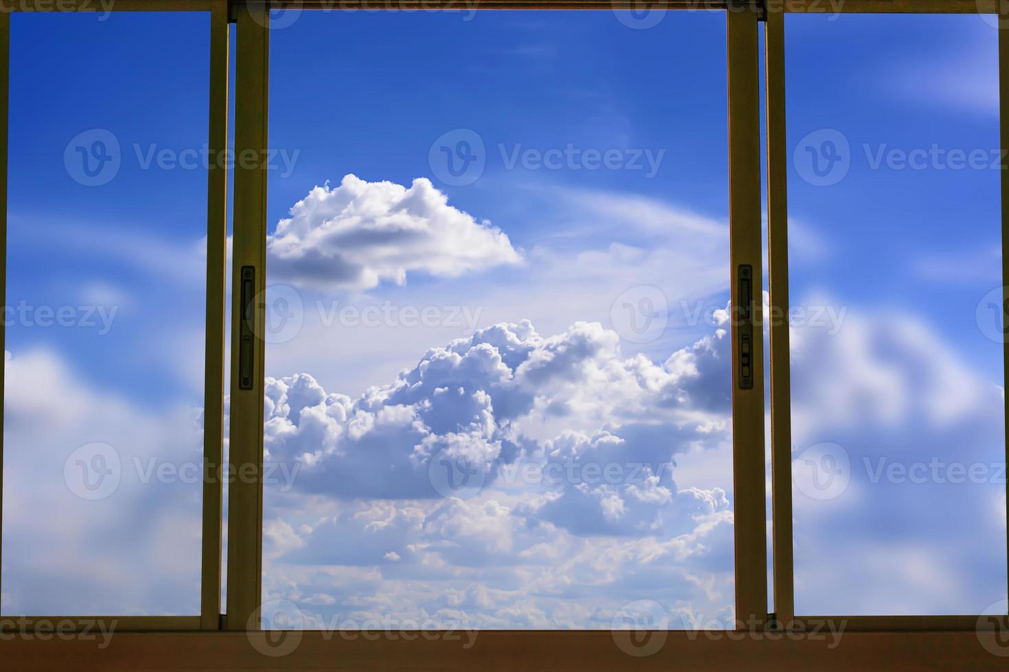 kijk naar de blauwe bewolkte lucht in het raam foto