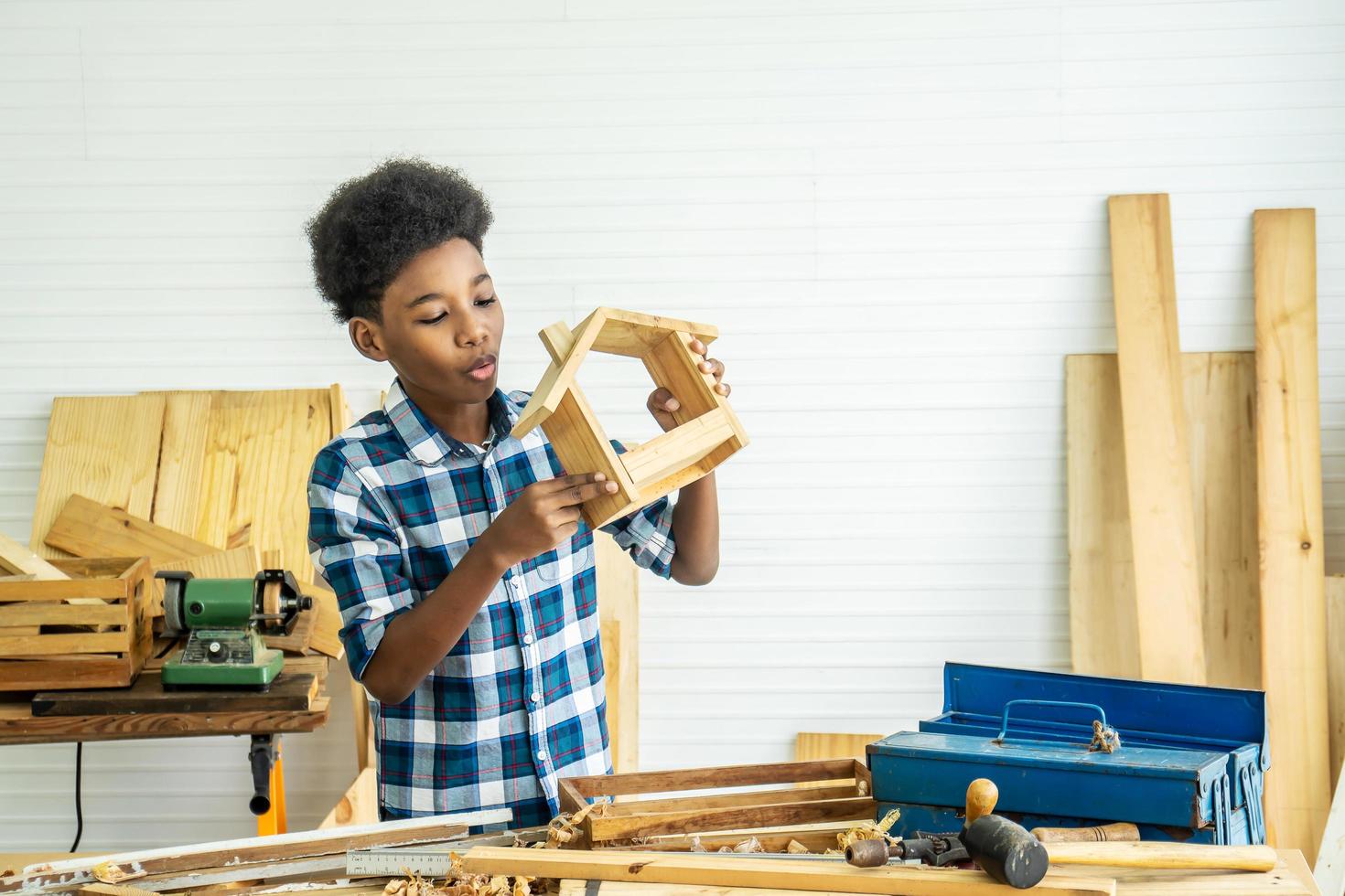 lachende Afro-Amerikaanse jongen timmerman blij met hout en schuurpapier foto
