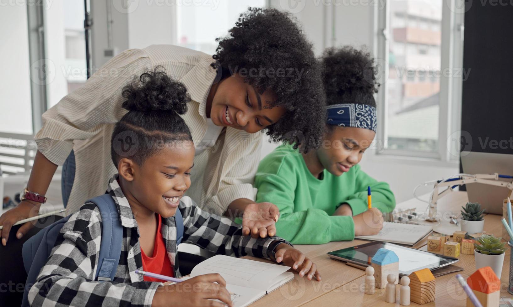 afro-amerikaanse vrouwelijke leraar die staat met leerlingen die schrijfles geven in een modern klaslokaal. foto