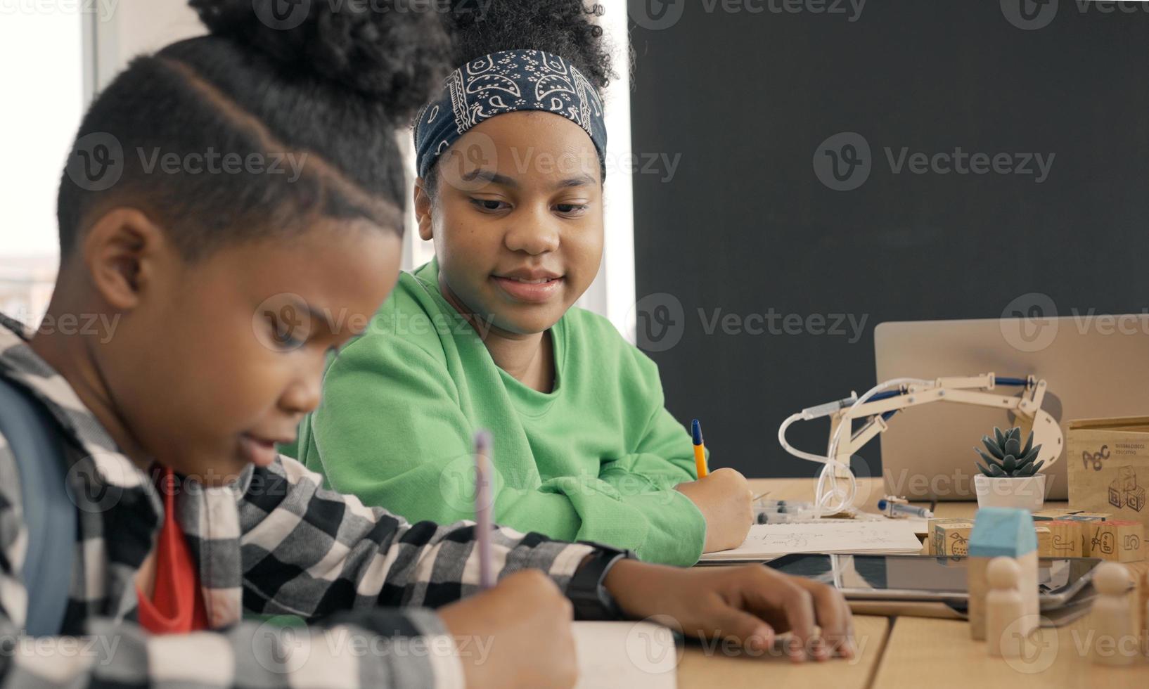 student in de internationale kleuterschool die samen een boek schrijft in de basisschoolklas, leerlingen genieten van studeren in de klas. foto