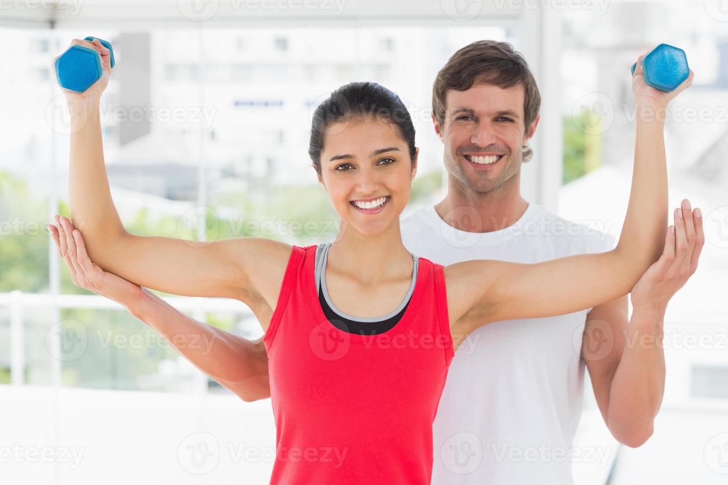 lachende instructeur met vrouw halter gewichten op te heffen foto