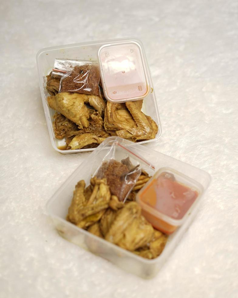kip omwikkeld met Indonesische kruiden. stukjes kip zijn klaar om gebakken te worden. kant-en-klaar voedsel in doosverpakking compleet met chilisaus enz. voedselverpakking mockupdoos voor sjabloon. focus vervagen. foto