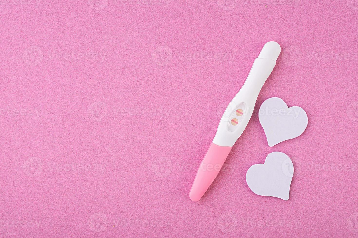 positieve zwangerschapstest met harten geïsoleerd op roze achtergrond foto