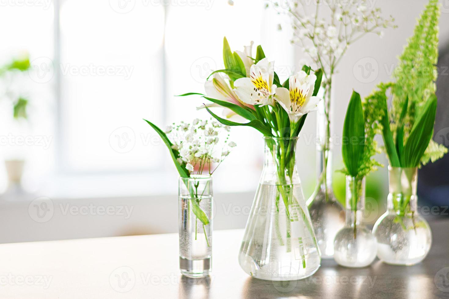 mooie lentebloemen in vazen op lichte achtergrond foto