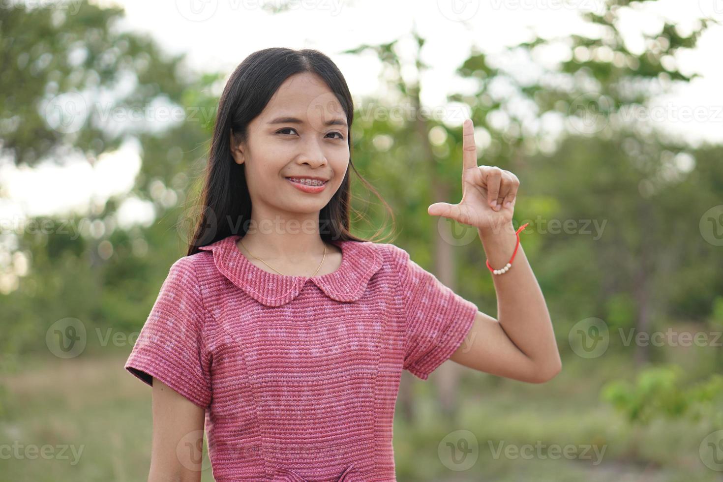 aziatische vrouw die lacht, steekt vrolijk je hand op naar de hemelachtergrond foto