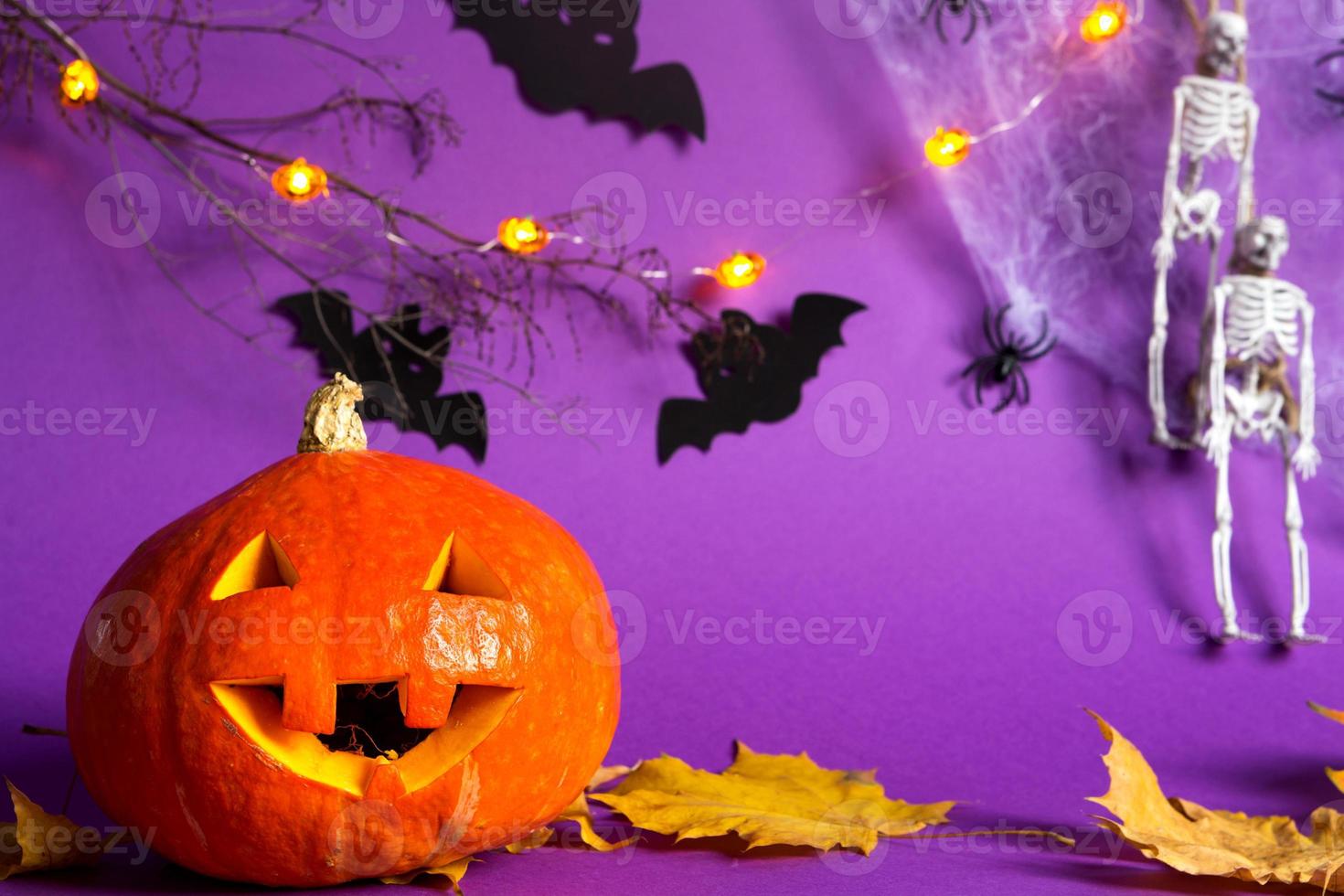 halloween achtergronden van jack lantaarn pompoen, spinnenweb, skelet aan een touw, spinnen en zwarte vleermuizen op een paarse achtergrond met verschrikkelijk landschap. horror en een enge vakantie met kopieerruimte foto