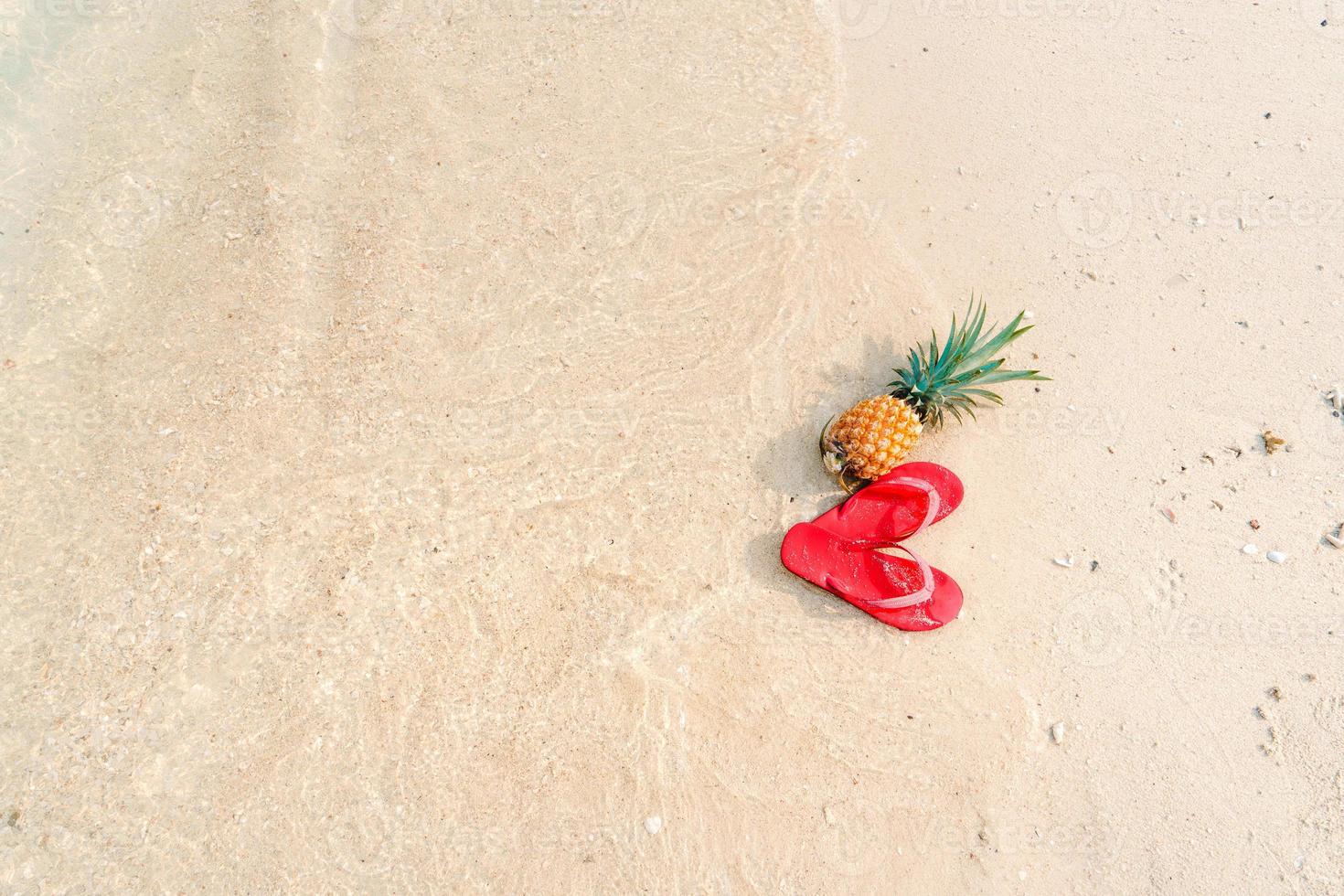 zomer strandvakantie met ananas en slippers op het strand foto