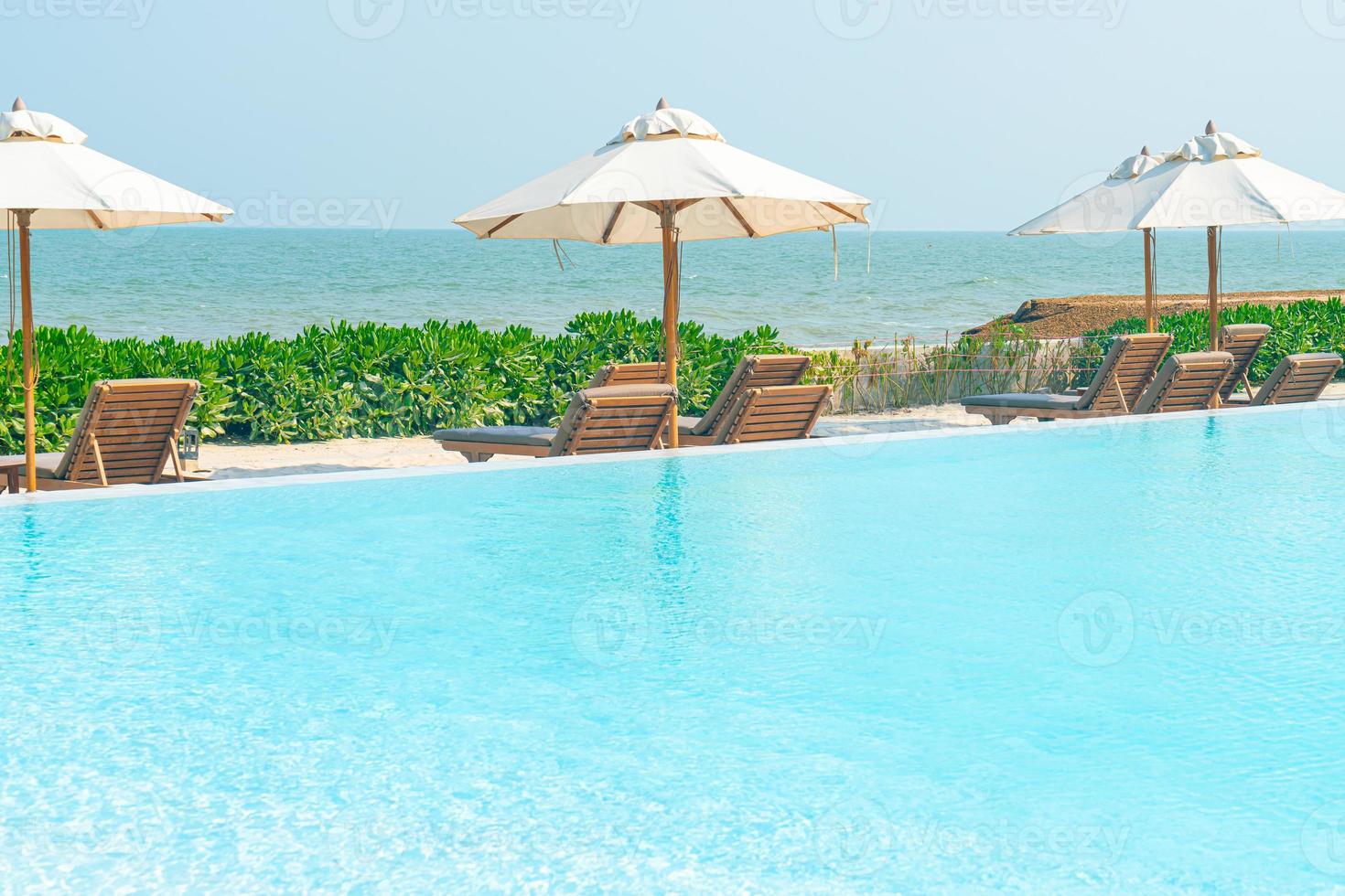 parasol met bed zwembad rond zwembad met oceaan zee achtergrond foto
