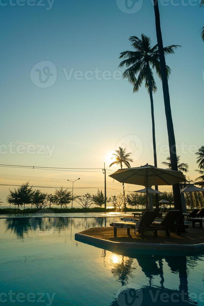 parasol met bed zwembad rond zwembad met oceaan zee achtergrond foto