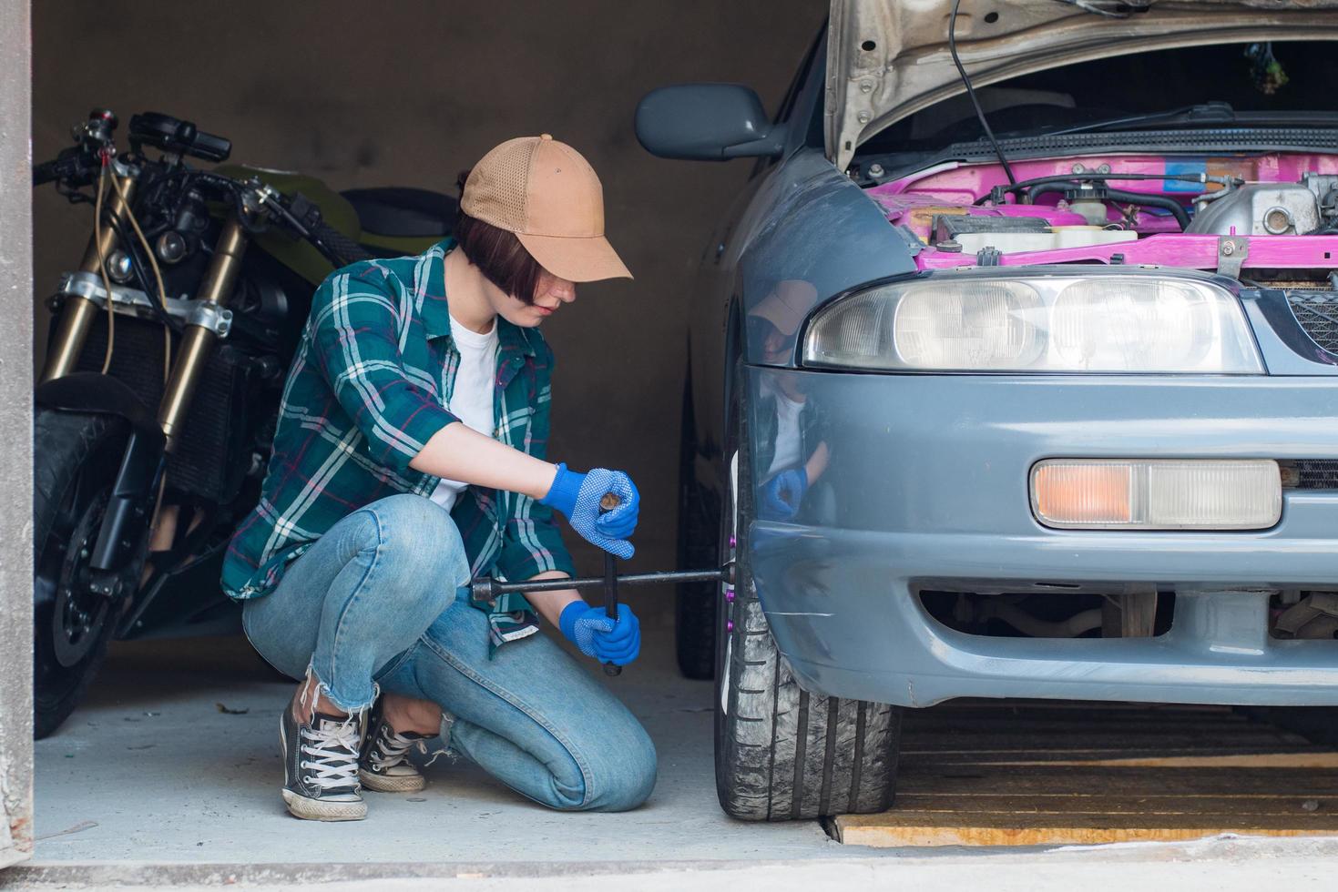 vrouwelijke monteur die auto in een garage repareert foto