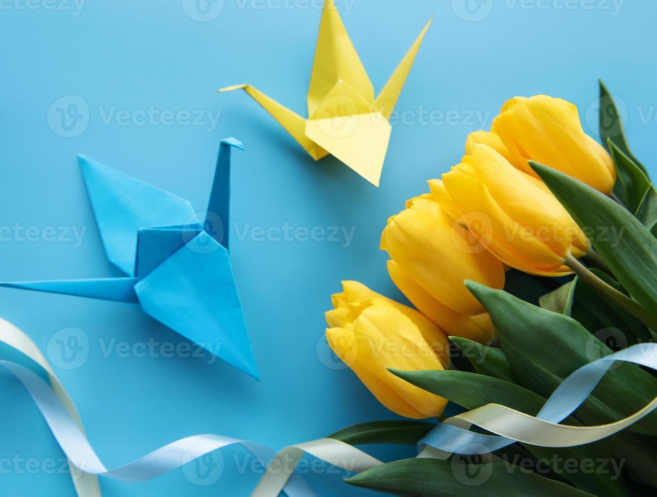 gele tulpen en origami papieren vogels op een blauwe achtergrond foto