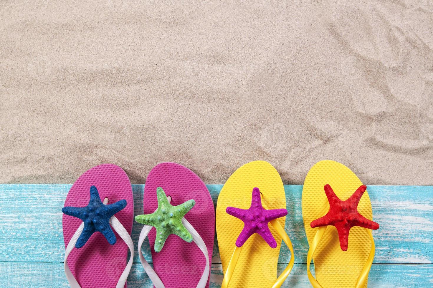 zand kopie ruimte. zand achtergrond bovenaanzicht. veelkleurige zeester op strandslippers foto