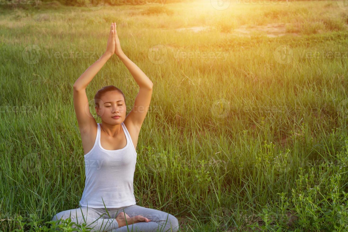 yoga in de stad mooie jonge fitte vrouw die sportkleding draagt, mediteert, ademt, zit met gekruiste benen in halve lotushouding op straat op zomerdag, ardha padmasana, kopieer ruimte foto