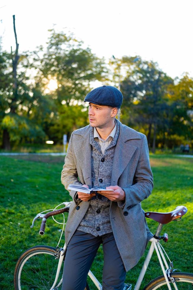 jonge mannelijke hipster leesboek in herfstpark foto