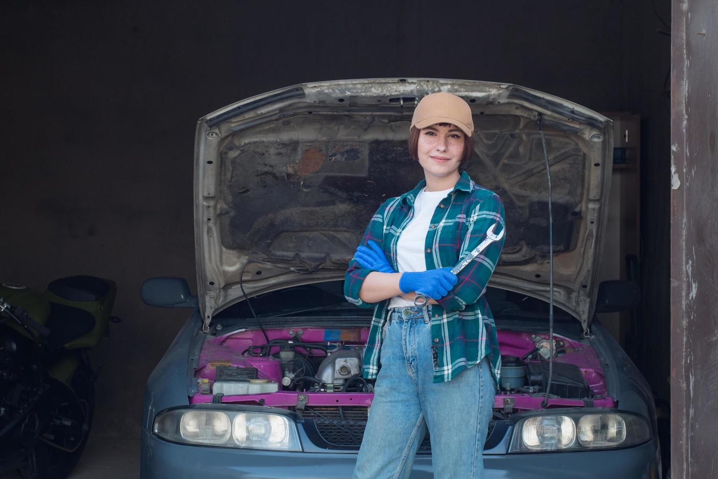 vrouwelijke monteur die auto in een garage repareert foto