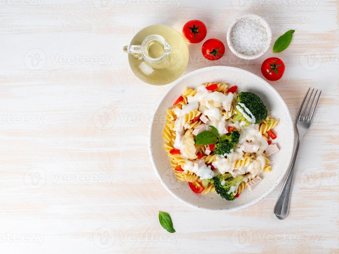 Pasta fusilli met groenten, vlees, witte saus op witte houten tafel, caloriearm dieet, vetarm voedsel, bovenaanzicht, kopieer ruimte foto