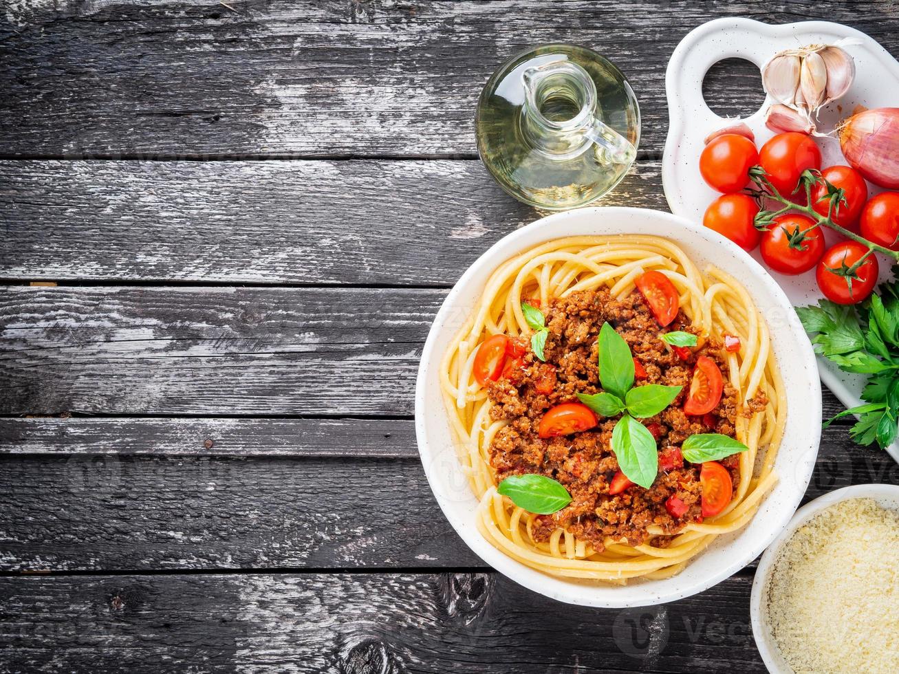 pasta bolognese met tomatensaus, rundergehakt, basilicumblaadjes op de achtergrond foto