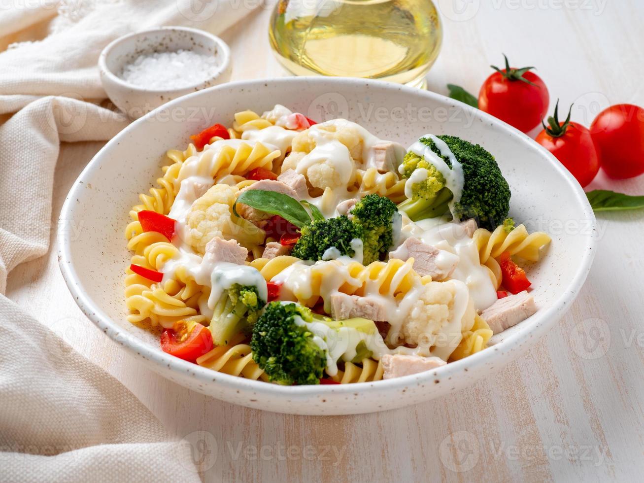 Pasta fusilli met groenten, gekookt gestoomd vlees, witte saus op witte houten tafel, caloriearm dieet, vetarm dieet, zijaanzicht foto
