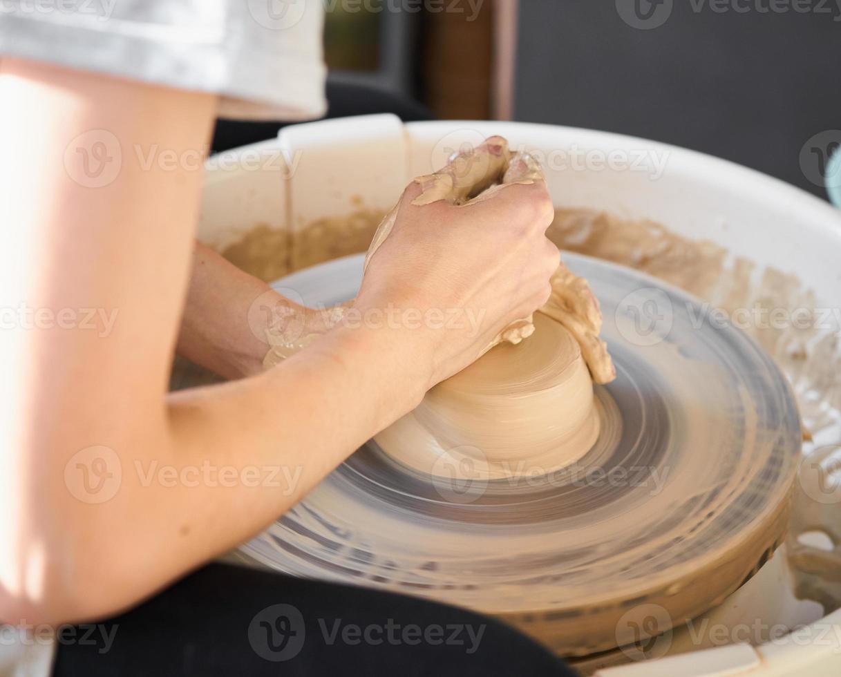 vrouw die keramisch aardewerk op wiel maakt, handen close-up, creatie van keramiek foto