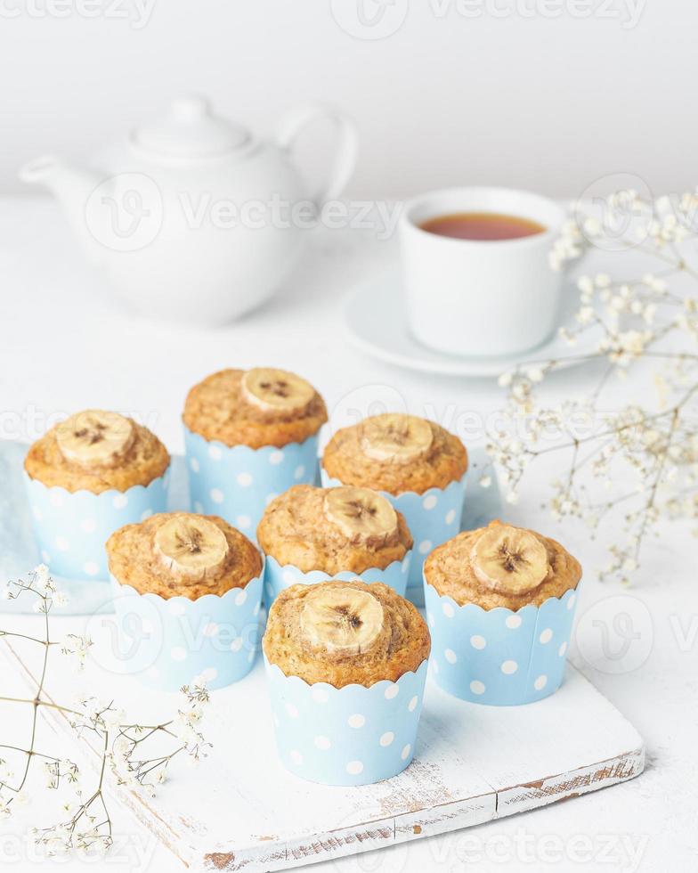 bananenmuffin, cupcakes in blauw cakevormpapier, zijaanzicht, verticale, witte betonnen tafel foto